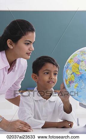 Stock Image - teacher and student look at globe. Fotosearch