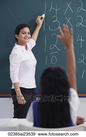 Stock Photo - teacher at chalkboard, girl raises hand. Fotosearch