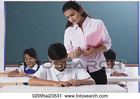 Stock Image - teacher overlooking schoolwork. Fotosearch
