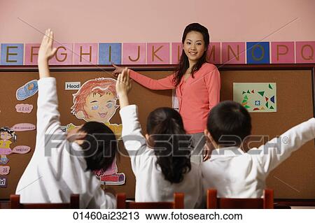 Teacher teaching alphabet with students raising hands in class View Large Photo Image Stock Image - Teacher teaching alphabet with students raising hands in class. Fotosearch