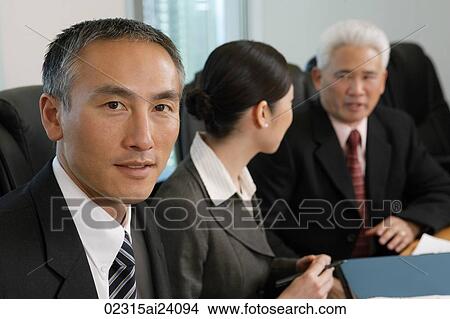 Picture - three colleagues at conference table. Fotosearch