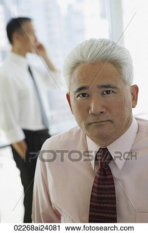 Stock Image - two businessmen, one on phone. Fotosearch