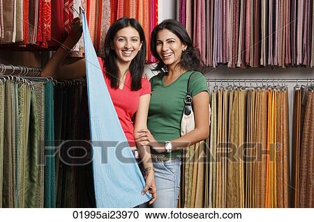 Stock Image - two girls shopping for fabric. Fotosearch