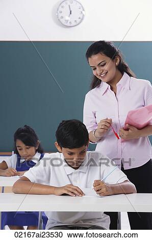 two students at desk, teacher standing View Large Photo Image Stock Image - two students at desk, teacher standing. Fotosearch