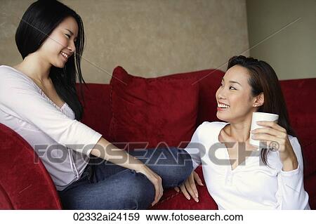 Stock Photo - two woman chatting, one on floor. Fotosearch