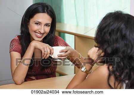 Picture - two young woman having coffee. Fotosearch
