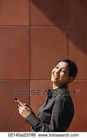 Stock Photograph - woman holding mobile phone, laughing. Fotosearch