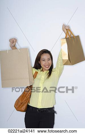 Stock Image - woman holding up shopping bags. Fotosearch