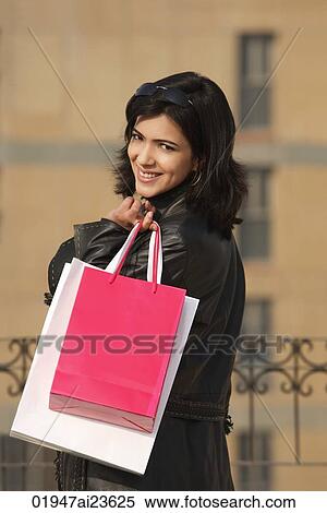 Stock Photography - woman looking back with shopping bags over shoulder. Fotosearch