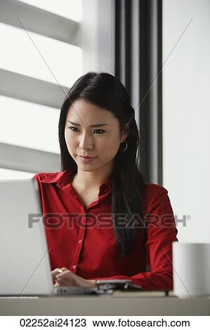 Stock Image - woman looking down at computer screen. Fotosearch