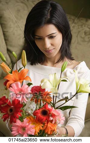 Stock Image - woman looks down at bouquet of flowers. Fotosearch