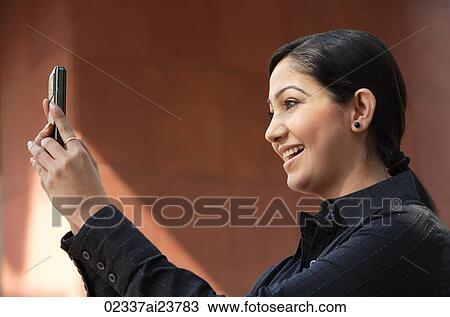 Stock Image - woman reading messages, smiling (horizontal). Fotosearch