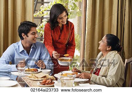 Stock Image - woman serves dinner to man and older woman (horizontal). Fotosearch
