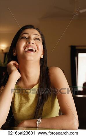 Stock Image - woman sitting at table and laughing. Fotosearch