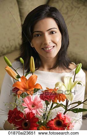 Stock Image - woman smiles holding bouquet of flowers. Fotosearch