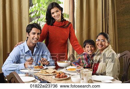 Stock Photograph - woman stands over dinner table with smiling family. Fotosearch
