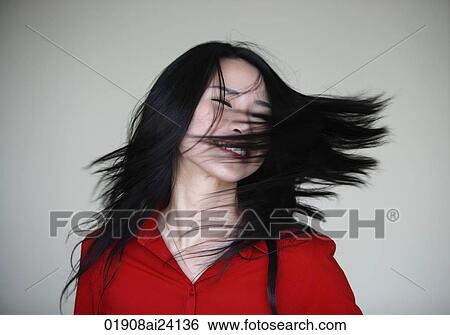 Stock Photograph - woman swinging her hair over her face. Fotosearch