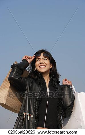 Stock Photograph - woman with arms full of shopping bags, sunglasses raised. Fotosearch