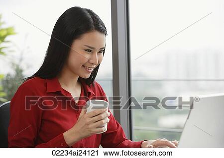 Stock Image - woman with coffee at laptop. Fotosearch