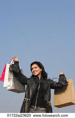 Stock Image - woman with shopping bags raised in air. Fotosearch