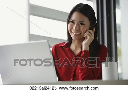 Stock Photography - woman working at laptop, on cell phone. Fotosearch