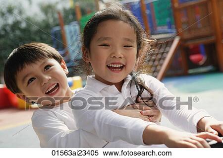 Stock Photography - Young boy and girl playing in playground. Fotosearch