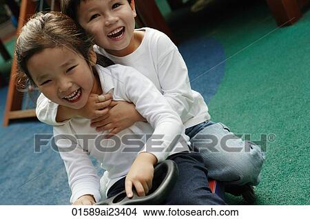 Young boy and girl ride on toy car in playground, looking at camera View Large Photo Image Picture - Young boy and girl ride on toy car in playground, looking at camera. Fotosearch