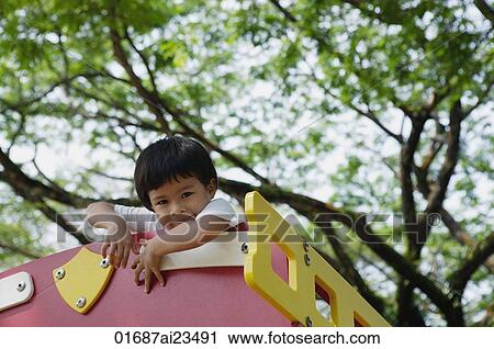 Young boy playing at the park, looking at camera View Large Photo Image Stock Image - Young boy playing at the park, looking at camera. Fotosearch