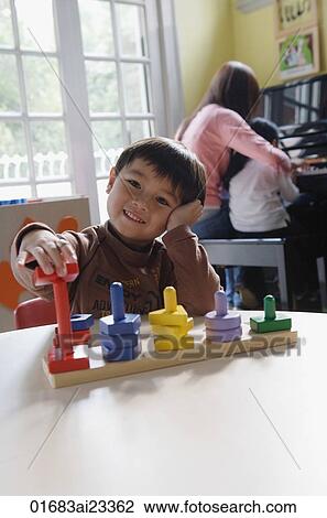 Young boy playing with building blocks, looking at camera View Large Photo Image Stock Image - Young boy playing with building blocks, looking at camera. Fotosearch