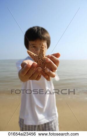 Young boy stretching out shell with both hands at the beach View Large Photo Image Stock Photograph - Young boy stretching out shell with both hands at the beach. Fotosearch