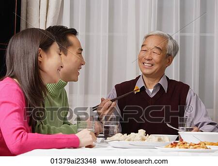Young couple and elderly father at dinner table View Large Photo Image Stock Photo - Young couple and elderly father at dinner table. Fotosearch