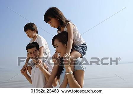 Young couple piggybacking children at the beach View Large Photo Image Stock Image - Young couple piggybacking children at the beach. Fotosearch