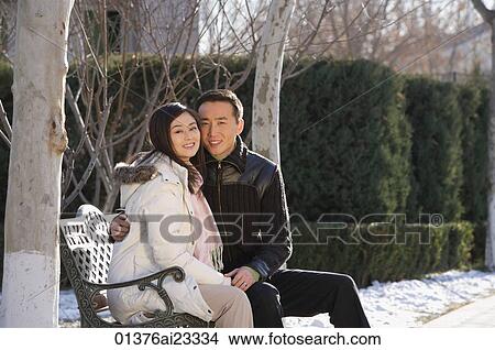 Young couple sitting on park bench View Large Photo Image Picture - Young couple sitting on park bench. Fotosearch