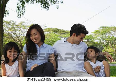 Stock Photo - Young family sitting on park bench. Fotosearch