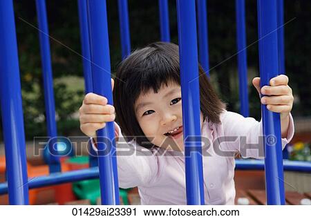 Young girl behind railings at playground smiling at camera View Large Photo Image Stock Image - Young girl behind railings at playground smiling at camera. Fotosearch