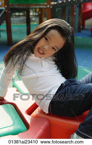 Stock Image - Young girl in playground, looking at camera. Fotosearch