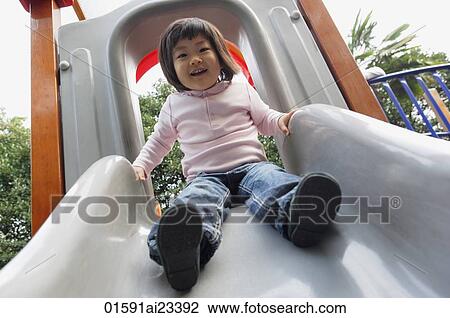 Stock Image - Young girl on top of the slide. Fotosearch