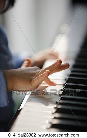 Stock Image - Young girl playing piano. Fotosearch
