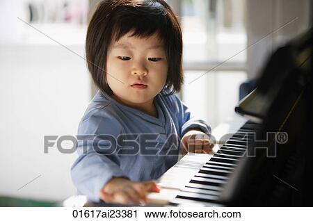 Stock Image - Young girl playing piano. Fotosearch