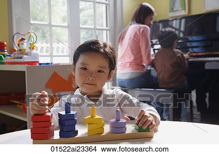 Picture - Young girl playing with building blocks, looking at camera. Fotosearch