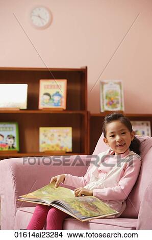 Picture - Young girl with book smiling at camera. Fotosearch