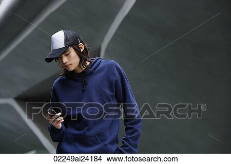 young man checking text messages, wearing cap View Large Photo Image Picture - young man checking text messages, wearing cap. Fotosearch