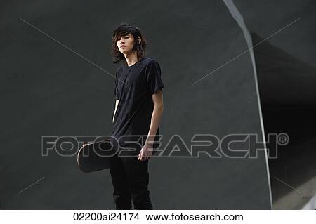 Picture - young man holding skateboard. Fotosearch