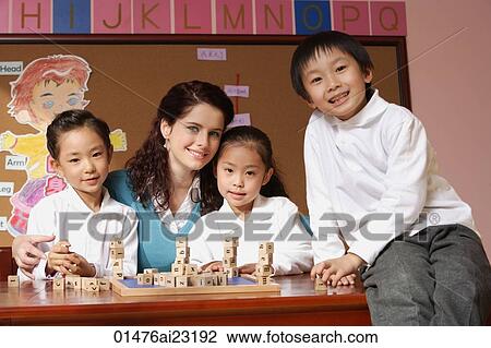 Stock Image - Young school children with their teacher in classroom. Fotosearch