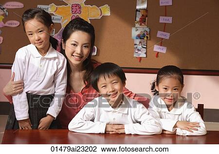 Stock Image - Young school children with their teacher in classroom. Fotosearch