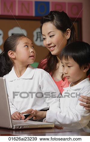 Young school children with their teacher using laptop View Large Photo Image Stock Photo - Young school children with their teacher using laptop. Fotosearch