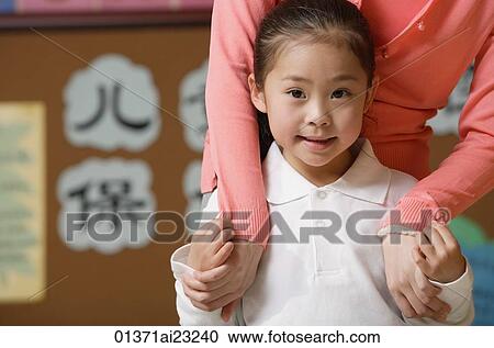 Young schoolgirl smiling at camera with teacher View Large Photo Image Stock Image - Young schoolgirl smiling at camera with teacher. Fotosearch