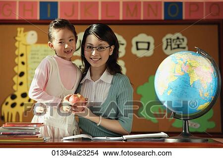 Picture - Young student giving teacher an apple. Fotosearch
