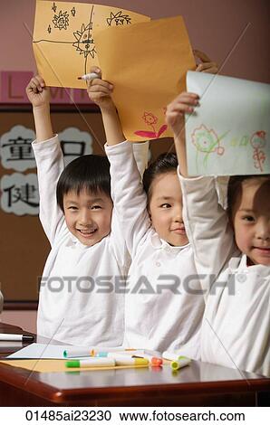 Stock Image - Young students showing off drawings. Fotosearch
