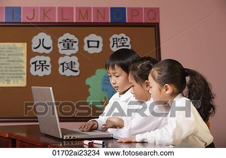 Picture - Young students using laptop in class. Fotosearch